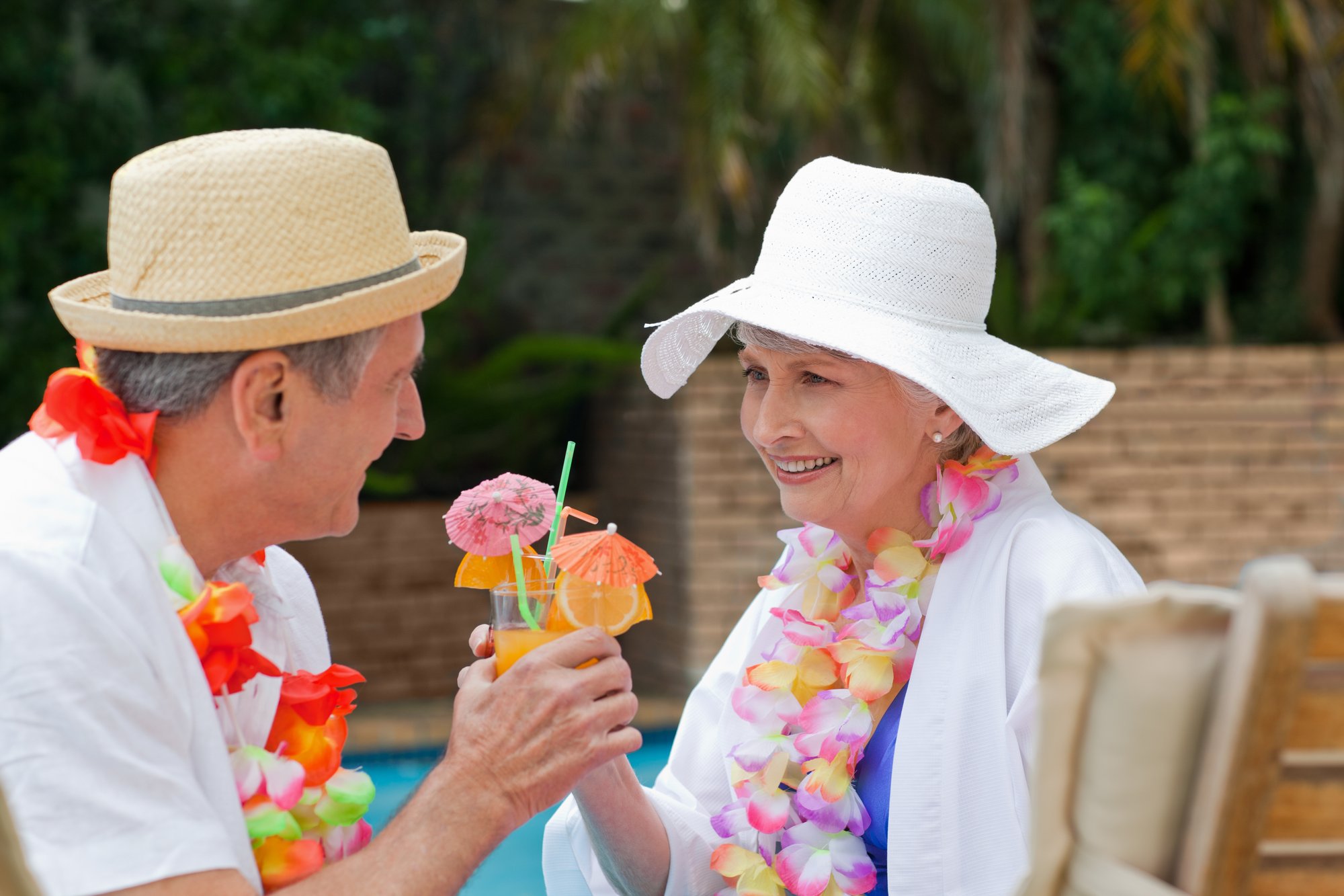 Outside on a beautiful day, two people having refreshing drinks, making a toast with their glasses